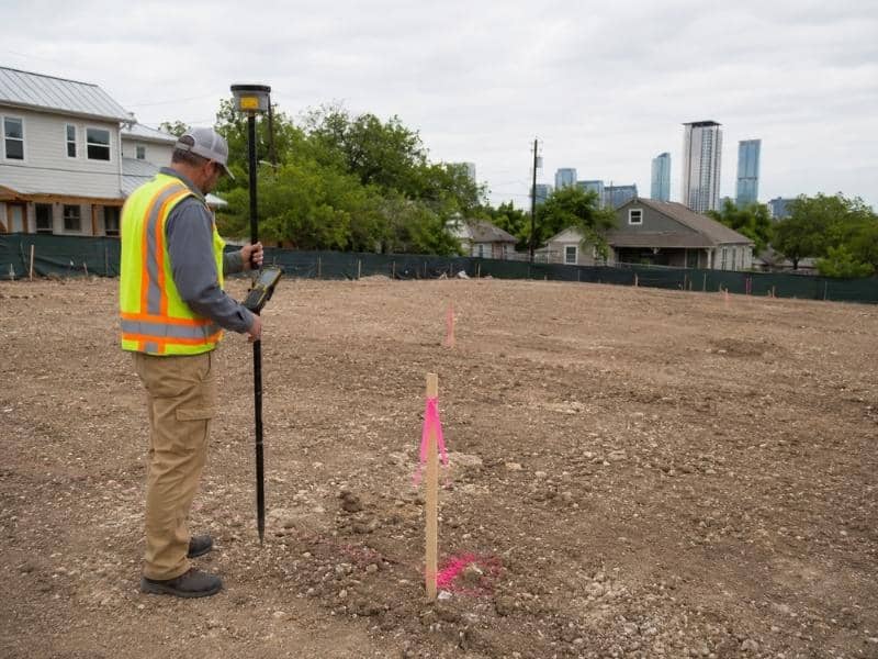 Boundary surveyor locating a marked property corner for a multi-unit development in Austin, Texas.